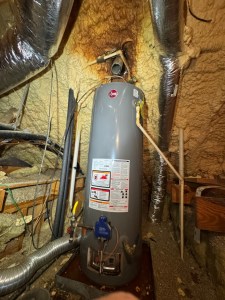 Tank-type water heater surrounded by spray foam insulation in a customer’s home. This unsafe setup could lead to carbon monoxide poisoning or fire.