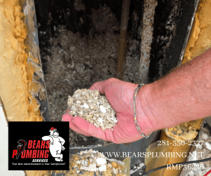Bear, owner of Bear’s Plumbing in Spring, Texas, holding heavy calcium and mineral buildup removed from a 20-year-old water heater, showing how hard water shortens water heater lifespan.