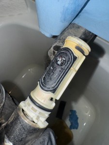 Hard water mineral buildup clogging a faucet cartridge, causing reduced water flow and low water pressure. Close-up of hard water mineral particles clogging a faucet cartridge, showing how scale buildup causes low water pressure and fixture damage.