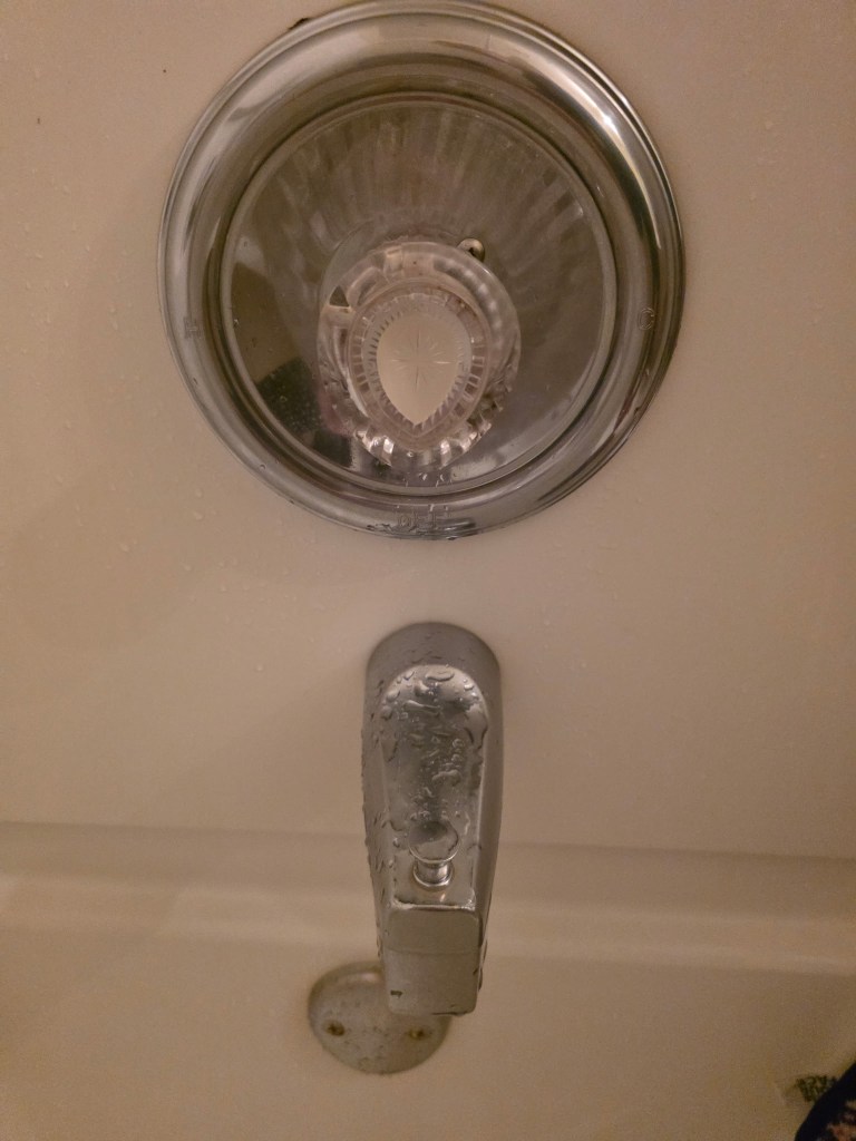 Single handle shower faucet with stiff handle caused by a worn or clogged cartridge affecting hot water flow.